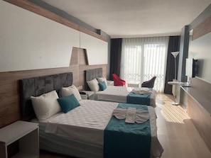 A hotel room with two beds, a red chair, a desk, and a TV. - Bozoogullari Otel (Batman)