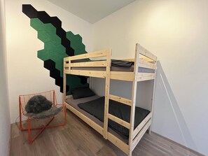 Ein Etagenbett mit einem Stuhl und einer geometrischen Wanddekoration.