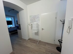 A hallway with a white door, a coat rack, a telephone, and a map on the wall. - Top 2 2 minutes from the Imperial Park, close to downtown, public transport. (Wien)