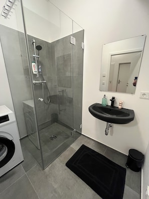 A modern bathroom with a glass-enclosed shower, a black sink, and a mirror above it. - Vrbo Property (Wien)