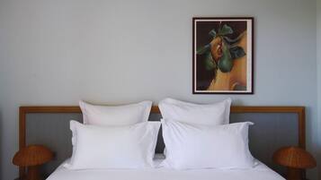 Una camera d'albergo con un letto, due cuscini, una testiera, un quadro appeso al muro e due lampade su comodini.