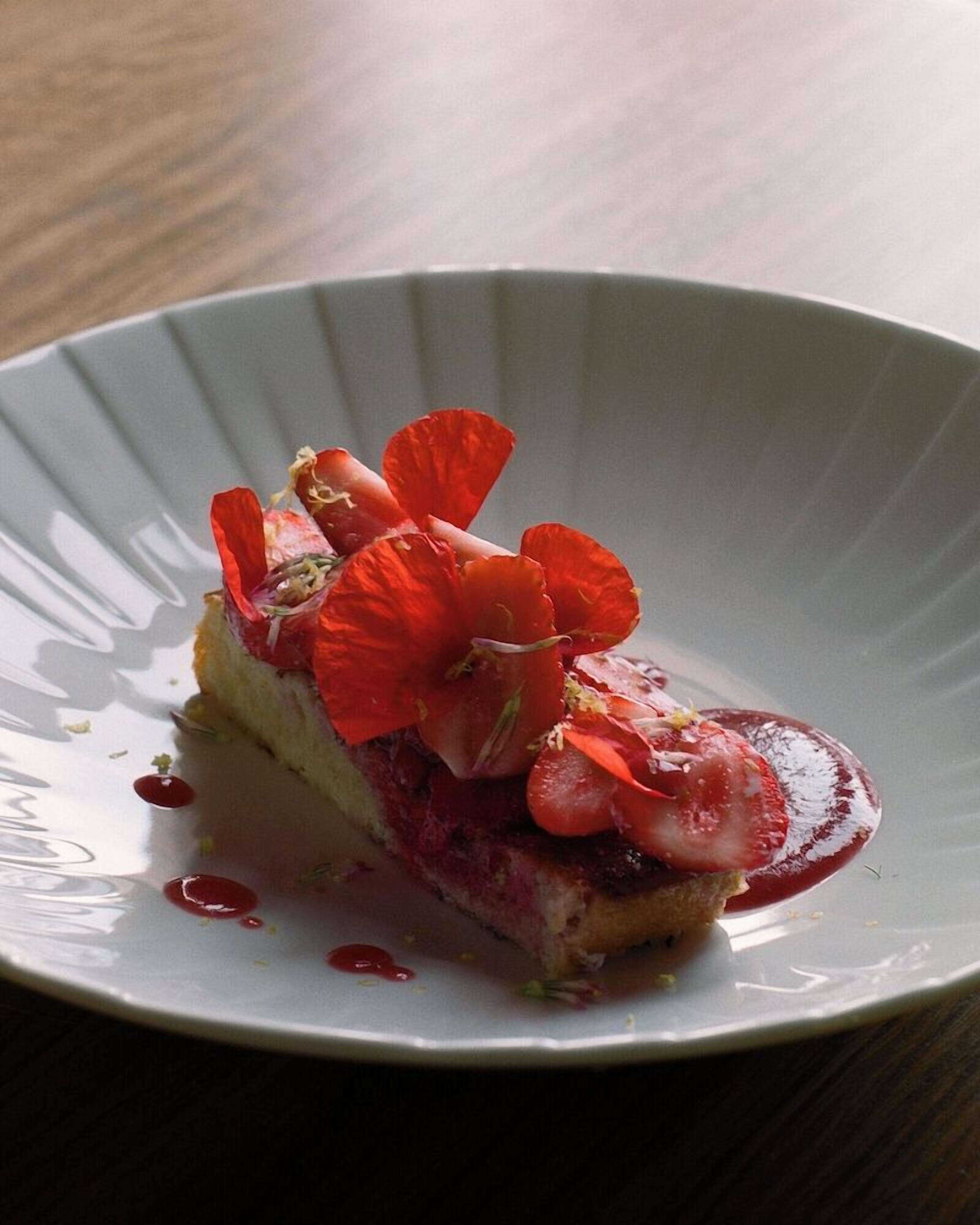 Un dessert su un piatto bianco con bordo a rilievo, posizionato su una superficie scura.