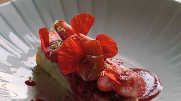Un dessert su un piatto bianco con bordo a rilievo, posizionato su una superficie scura.