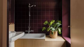 Un baño con bañera, lavamanos y una planta en maceta.