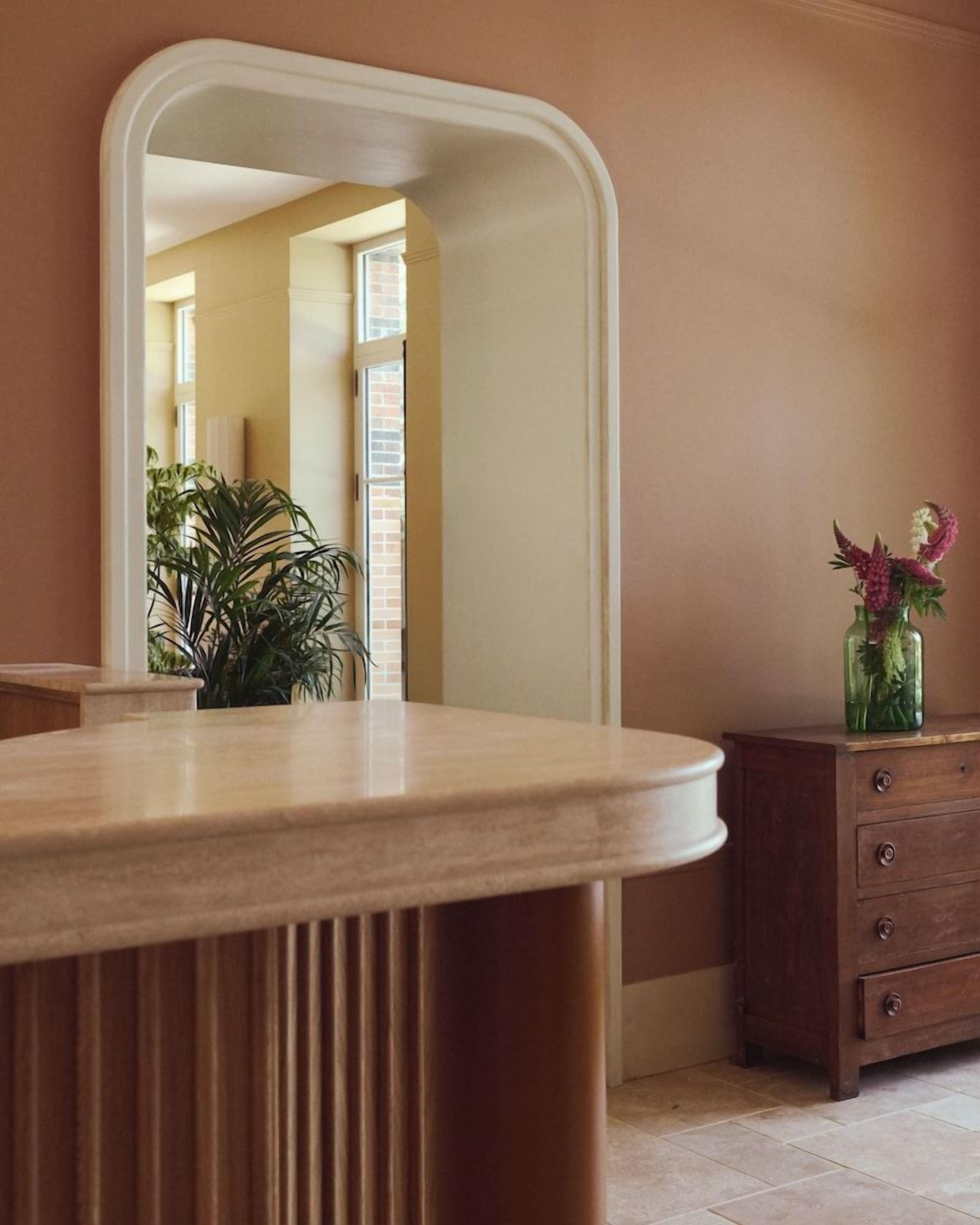 A bathroom with a round vanity, a mirror, a wooden cabinet, and a potted plant.