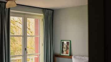 A bedroom with a bed, a ceiling fan, a window with curtains, and a framed picture on the wall.