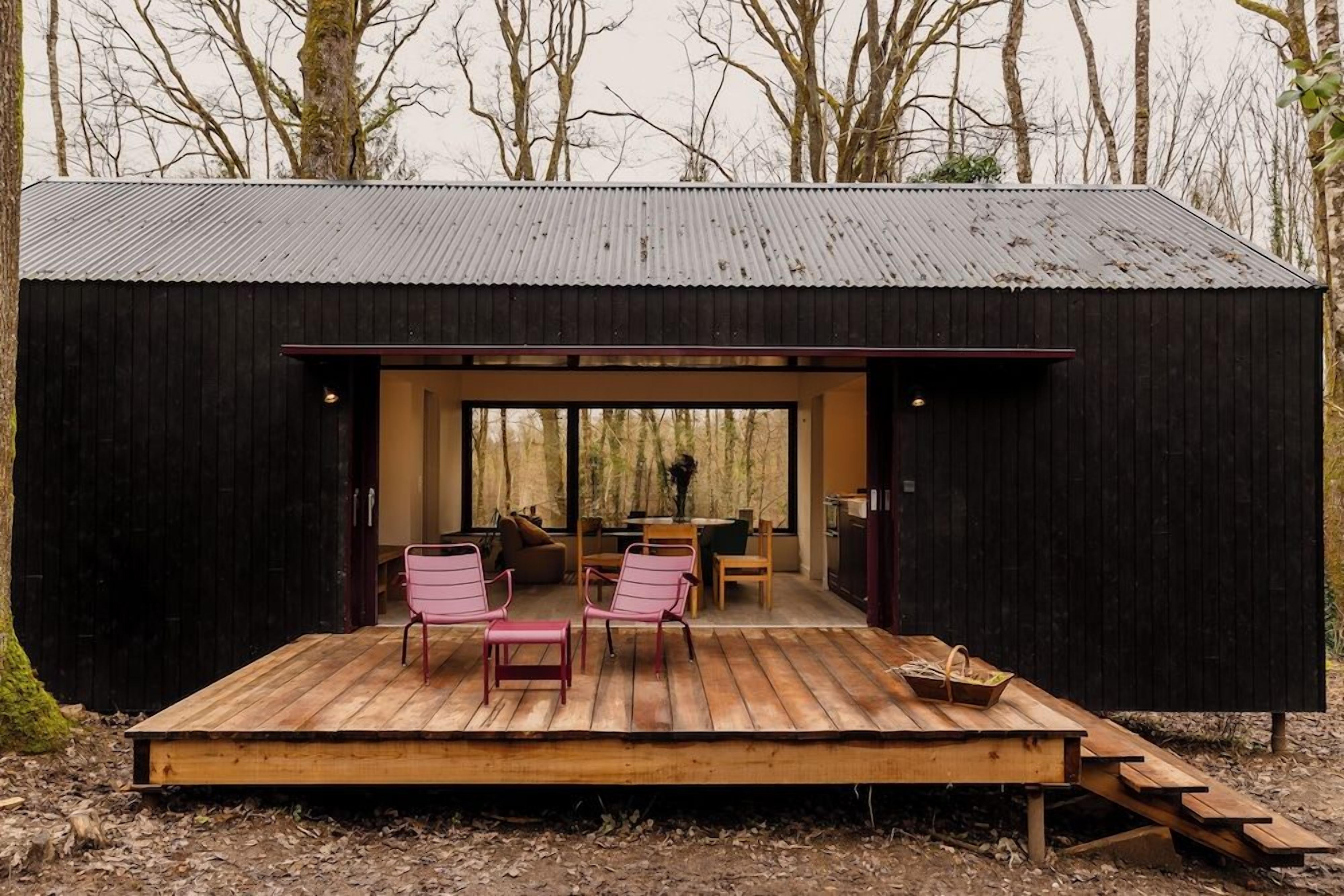 A cabin with a wooden deck, seating area, and a dining table.