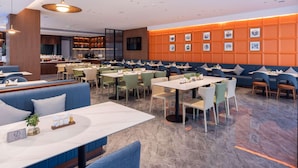 Un interior de restaurante moderno con cabinas, mesas y una zona de bar.