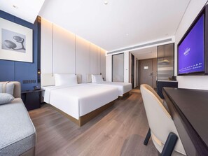 Une chambre d’hôtel moderne équipée d’un grand lit, de tables de chevet, d’un bureau et d’une télévision.
