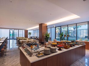 A modern dining area with a buffet setup, including various food items and a seating arrangement. - Mercure Jinan Beiyuan Street (Jinan)
