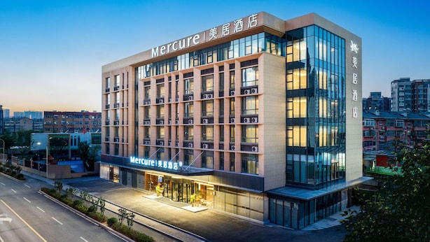 Un hotel moderno con señalización llamativa, varios pisos y una entrada bien iluminada.