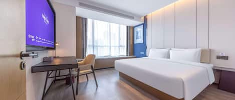 A hotel room with a bed, a desk, a chair, a television, and a window.