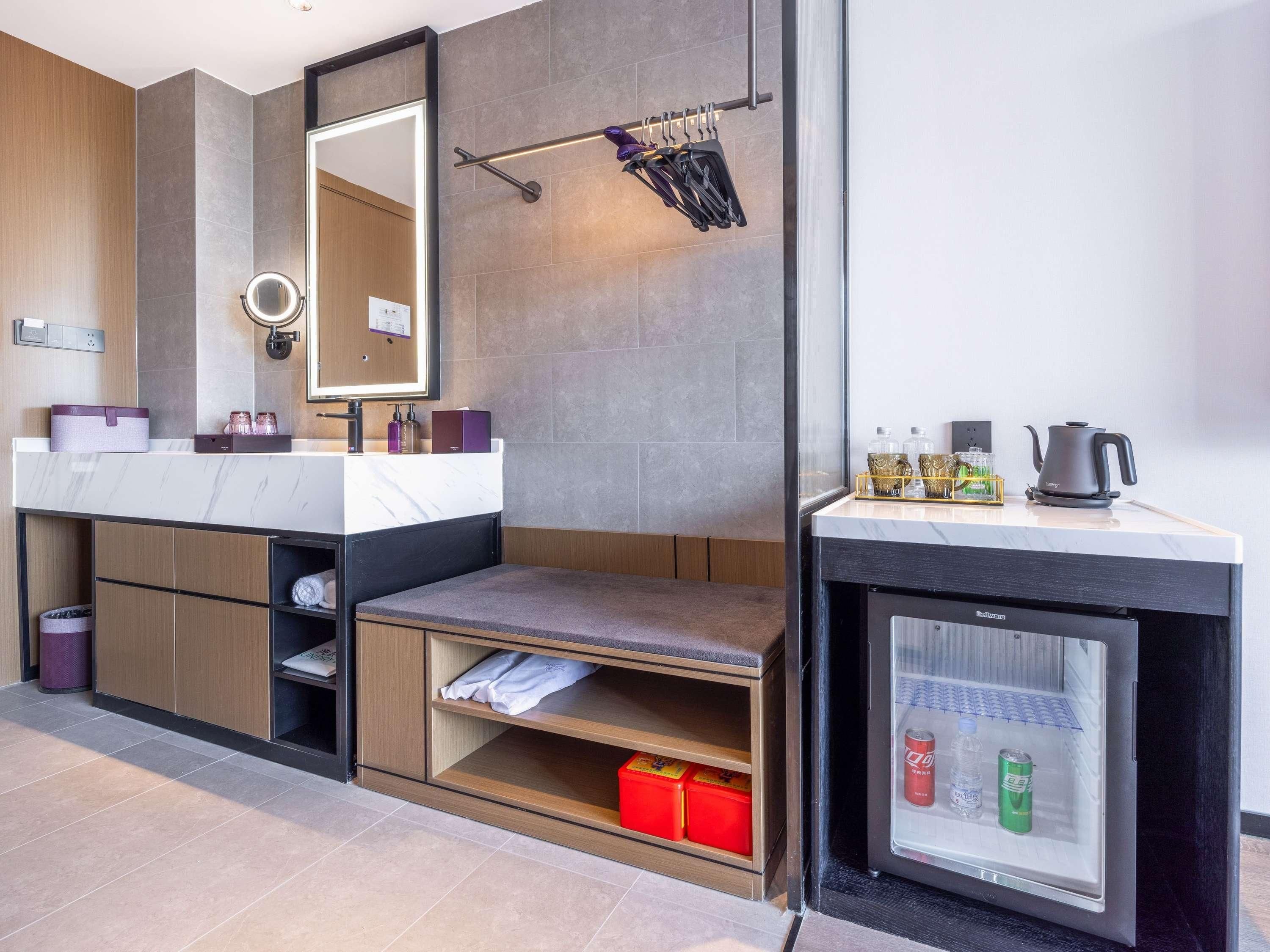 A modern bathroom with a vanity, mirror, towel rack, and a refrigerator with beverages.