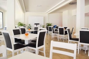 A spacious dining area with white tables and chairs, some with black cushions. - Bayu Balau Beach Resort (Bandar Penawar)