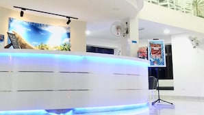 Bancada de recepção com placa indicando 'RECEPTION' e uma tela digital exibindo uma imagem panorâmica.