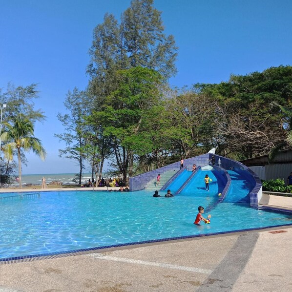 A swimming pool with a water slide and a beach view. - Bayu Balau Beach Resort (Bandar Penawar)