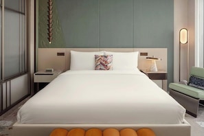 A hotel room with a large bed, a nightstand, a lamp, and a chair. - W Riyadh Kafd (Riyadh)