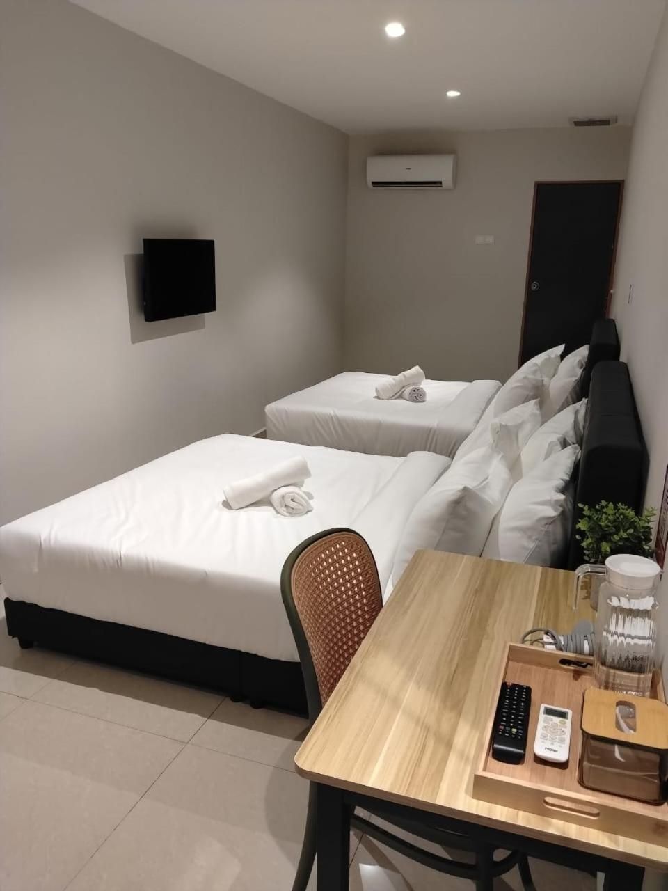 Een hotelkamer met twee bedden, een bureau, een stoel, een televisie en een airconditioningsysteem.