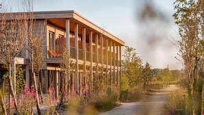 A modern building with a wooden facade, a balcony, and a pathway leading to it.