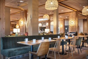 A modern restaurant interior with wooden beams, green upholstered seating, and pendant lighting. - Hotel le Bout du Parc de Versailles (Versailles)