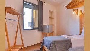 A room with two beds, a wooden shelf, a small table, a mirror, and a window with curtains. - Moon surf (Imsouane mroc)
