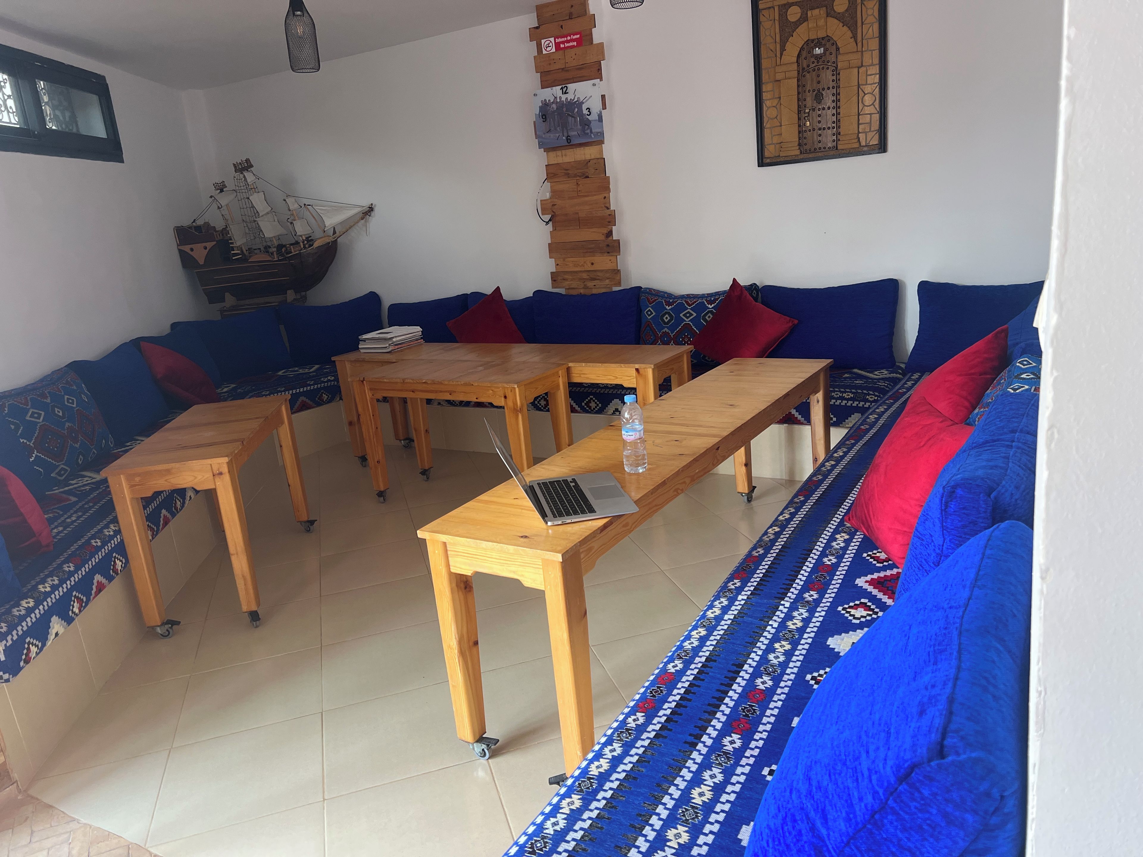 A living room with a sofa set, a wooden coffee table with a laptop, and a decorative ship model.