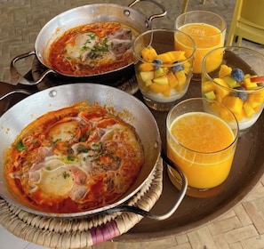 Ein Frühstückswagen mit zwei Behältern Essen, einem Glas Orangensaft und einer Schüssel Obst.