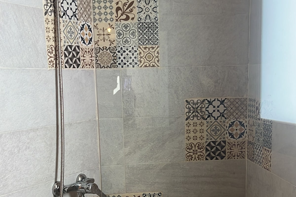 A shower with a handheld showerhead and a handheld showerhead with a hose.