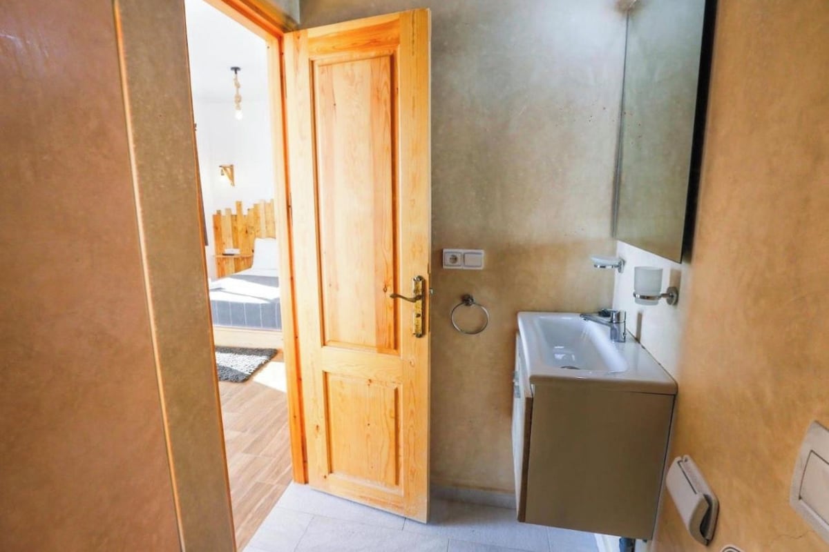 A bathroom with a wooden door, a sink, and a mirror.