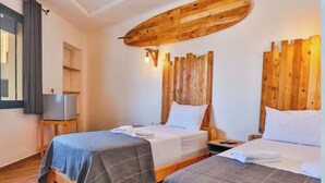 A hotel room with two beds, wooden headboards, a flat-screen TV on a small table, and a dark rug on the floor.