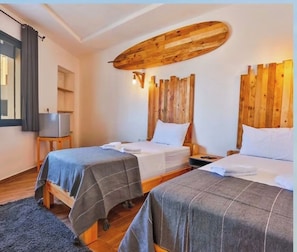 Een hotelkamer met twee bedden, houten hoofdeinden, een flatscreen televisie op een tafeltje en een donker vloerkleed.