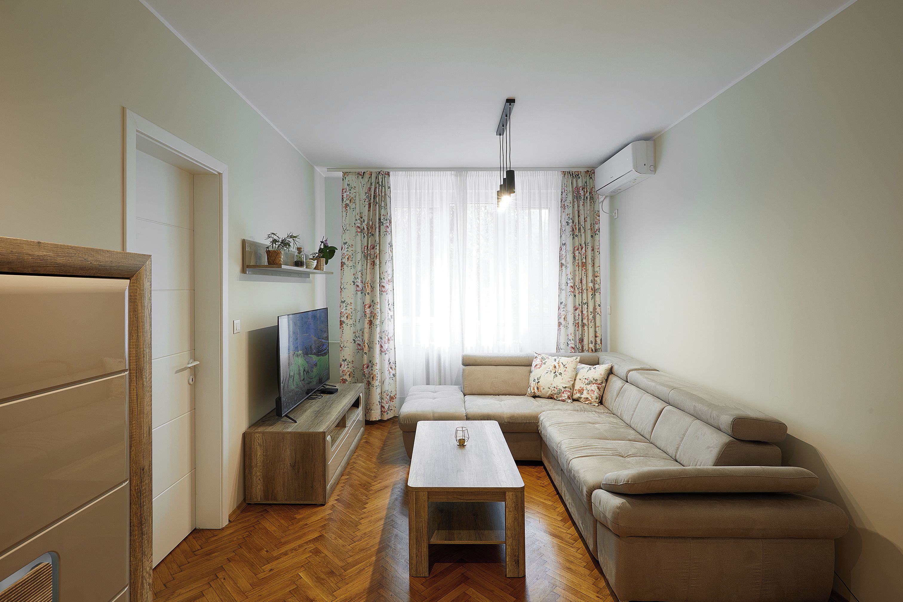 Ein Wohnzimmer mit einer Couch, einem Couchtisch, einem Fernseher und einem Holzschrank.