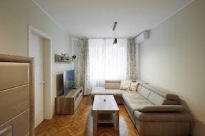 Ein Wohnzimmer mit einer Couch, einem Couchtisch, einem Fernseher und einem Holzschrank.