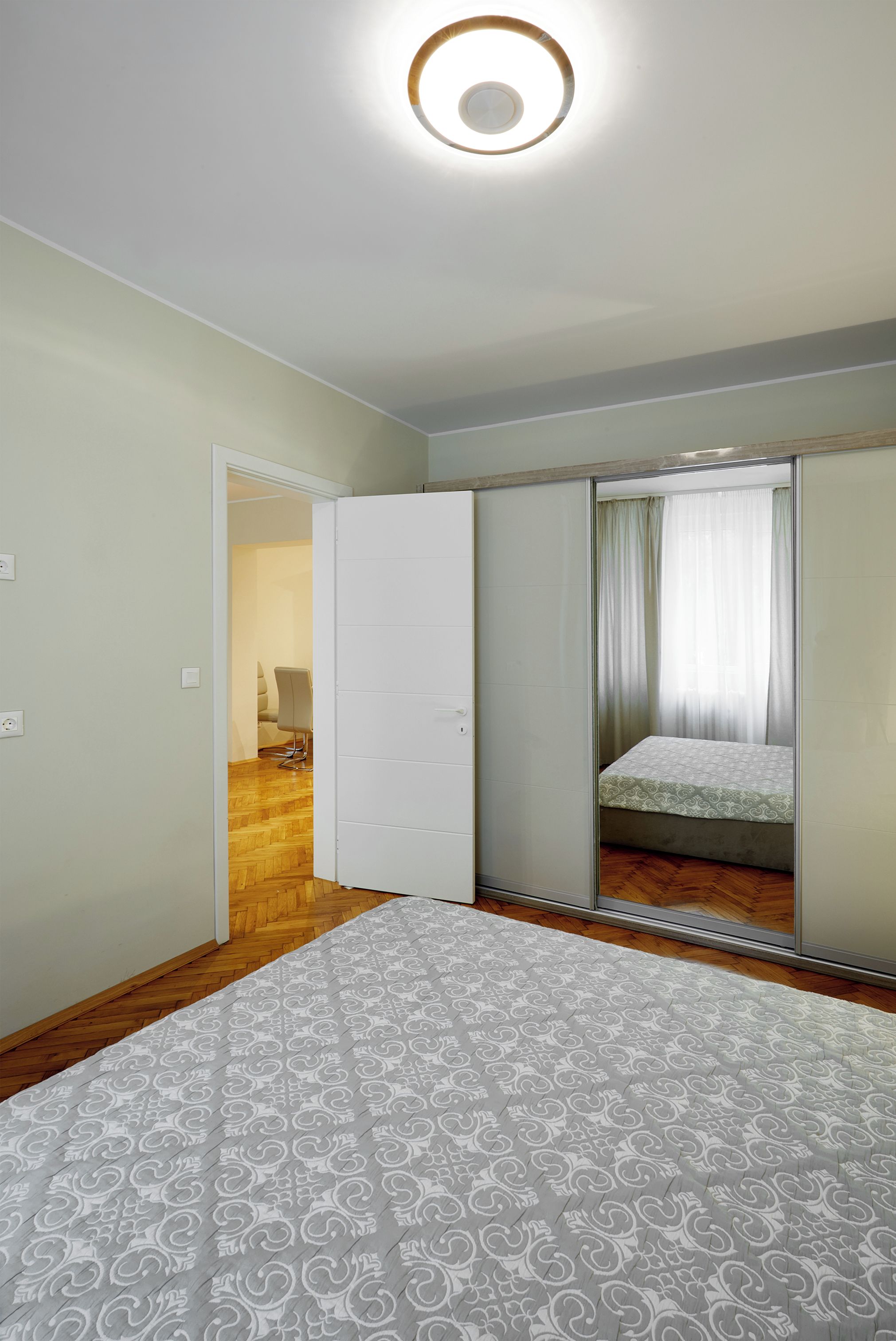 A bedroom with a bed, a wardrobe, and a door leading to another room.