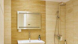 Un bany amb una paret de fusta, un lavabo blanc, un mirall, una dutxa i un vàter.