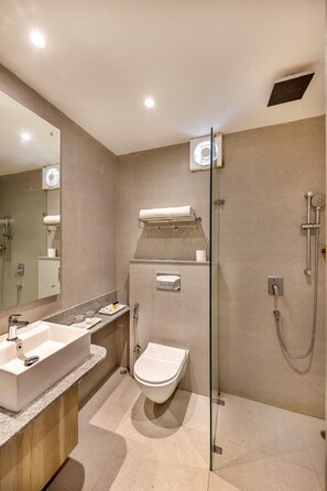 A modern bathroom with a glass-enclosed shower, a vanity with a sink, and a toilet. - Comfort Inn Grand (Ghaziabad)