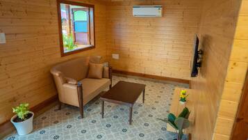 Une pièce chaleureuse avec un décor intérieur en bois, un canapé, une table basse et une fenêtre donnant sur un beau paysage.
