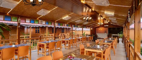 A restaurant with wooden interiors, multiple dining tables, and chairs.