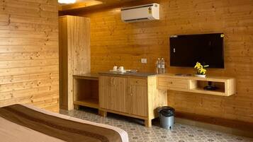 Une chambre avec un lit, une armoire en bois, un téléviseur et un ventilateur de plafond.