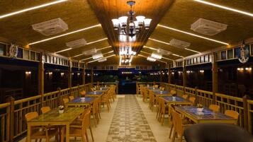 Un restaurant avec des tables et des chaises en bois, un sol à carreaux et un lustre.