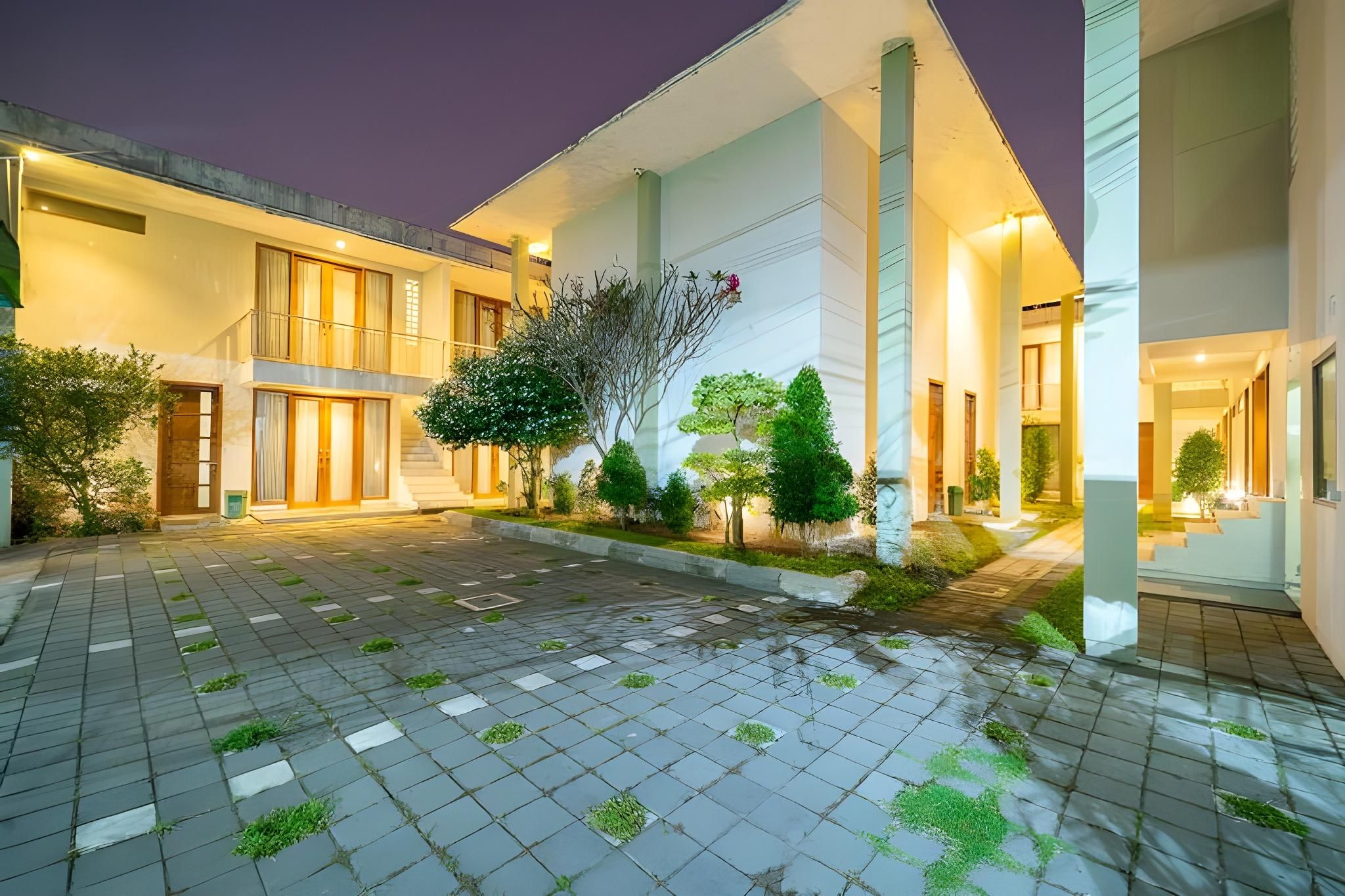 Un edificio moderno con patio central, que cuenta con una escalera principal, varias ventanas y una diversidad de plantas.