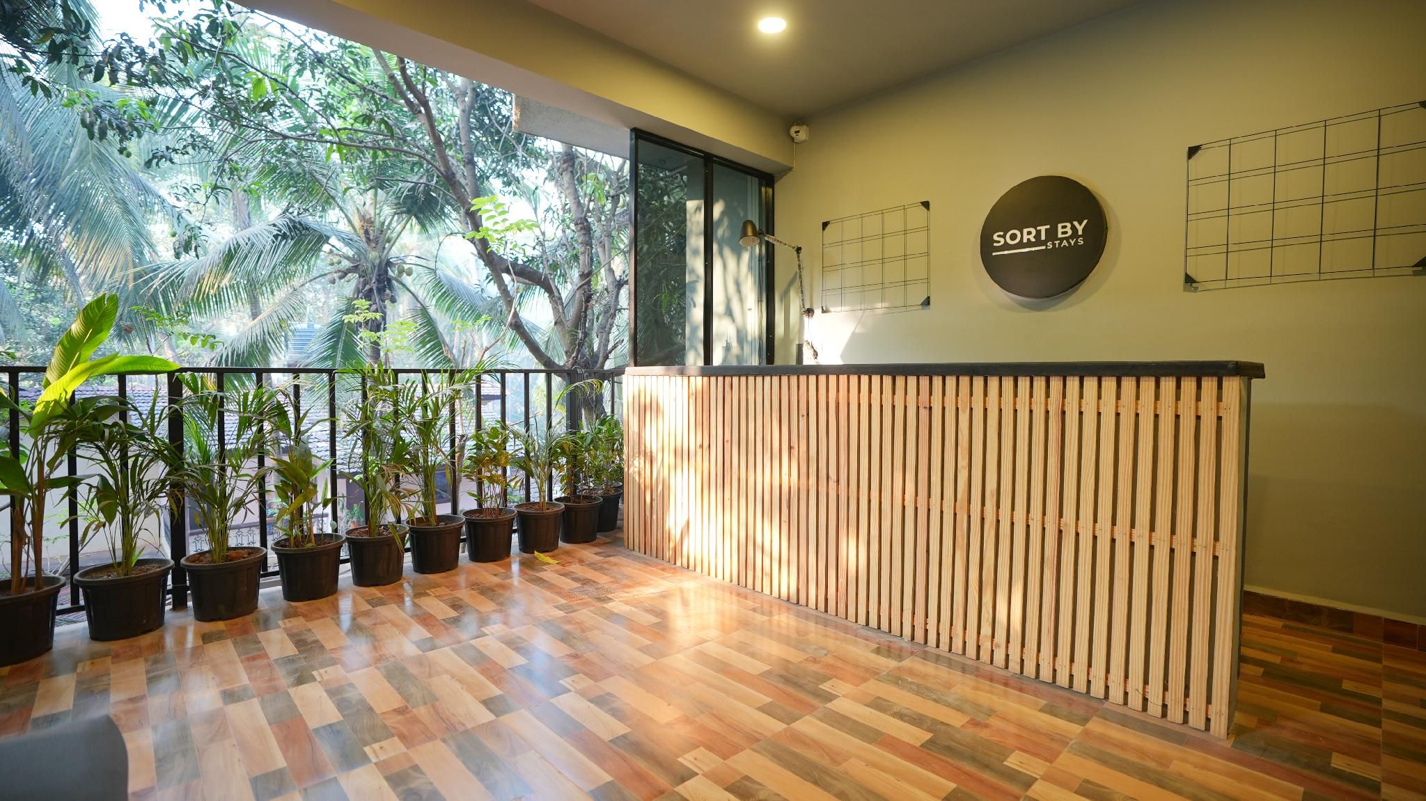 A reception area with a wooden reception desk, potted plants, and a view of trees through large windows.