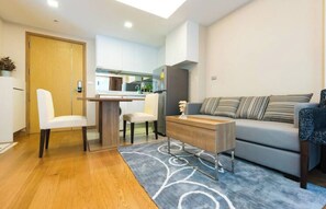 A modern living room with a sofa, a coffee table, and a dining area with chairs. - Resort Style Condo - Heart of Bangkok (Bangkok)