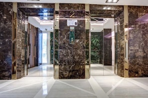 A modern elevator with marble walls and a digital display. - Resort Style Condo - Heart of Bangkok (Bangkok)