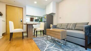 A modern living room with a sofa, two chairs, a coffee table, and a kitchen area in the background.