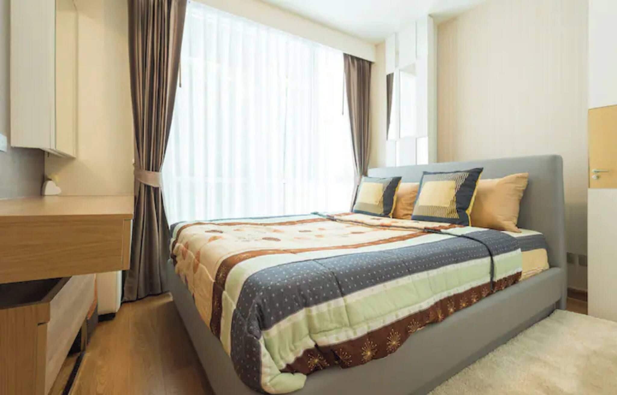 A hotel room with a bed, a desk, and a window with curtains.