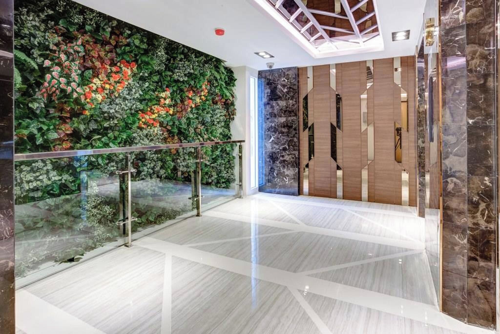A modern interior with a glass railing, a wall with a floral mural, and a geometric floor pattern.
