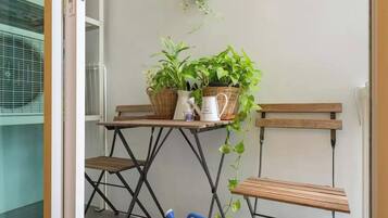A small outdoor seating area with a table, two chairs, and potted plants.