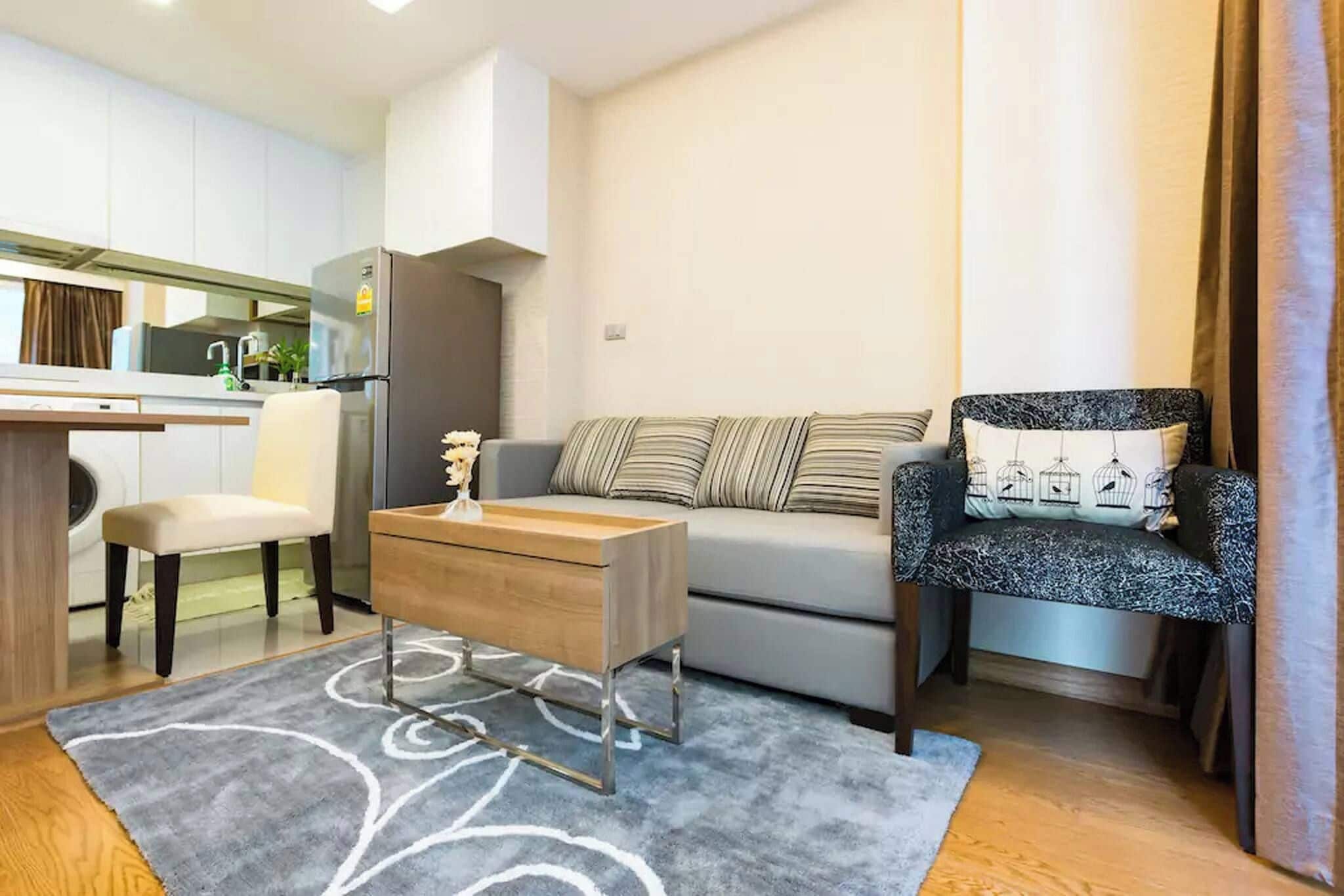 A compact living space with a kitchenette, a sofa, a chair, and a coffee table.