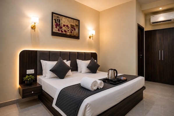 Una habitación de hotel moderna con una cama grande, lámparas de noche, un cuadro y una mesa de centro con artículos de cortesía.